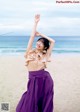 A woman standing on a beach with her arms outstretched.