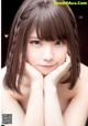 A young woman with long brown hair and bangs posing for a picture.