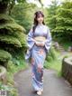 A woman in a blue kimono walking down a path.