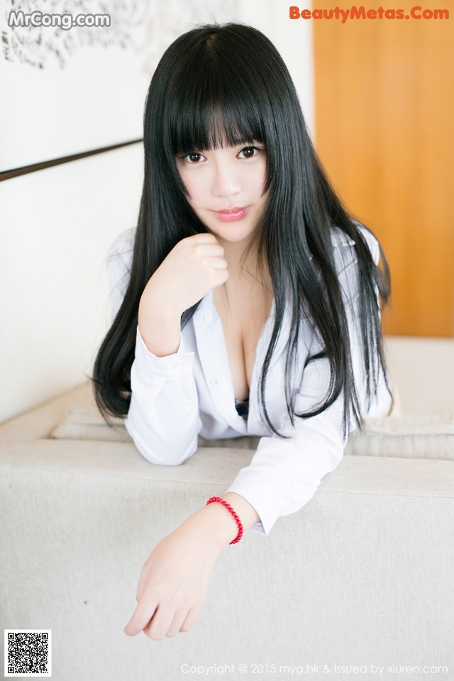 A woman with long black hair sitting on a couch.