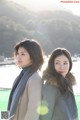 Two young women standing next to each other near a body of water.