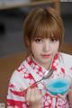 A woman holding a bowl of blue liquid and a spoon.