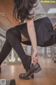 A woman in a school uniform is putting on her shoes.