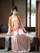 A woman in a pink and orange dress sitting on a window sill.