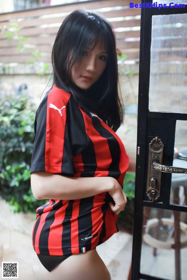 A woman in a red and black striped shirt is posing for a picture.