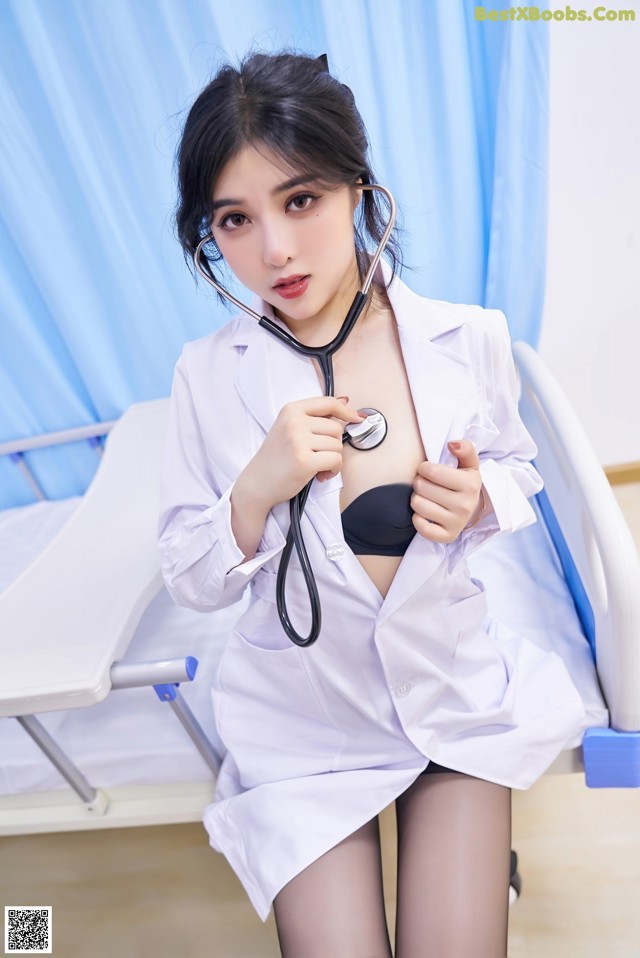 A woman in a white lab coat holding a stethoscope.