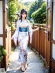 A woman in a kimono standing in front of a wooden door.